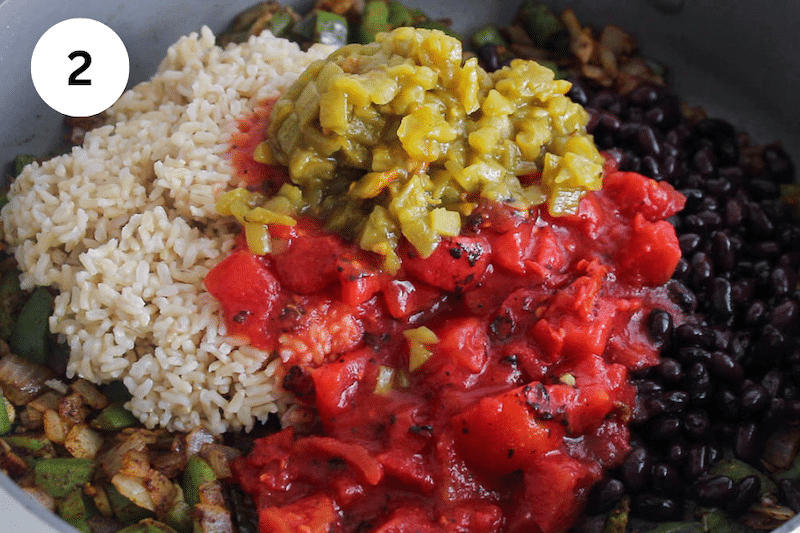 A large pan with bean, rice, tomatoes and green chiles.
