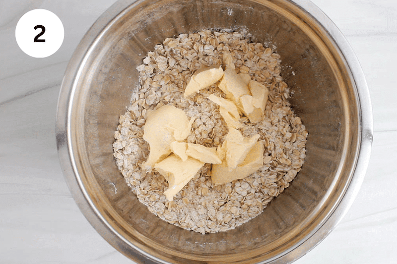 A large bowl with oat and flour topped with vegan butter.