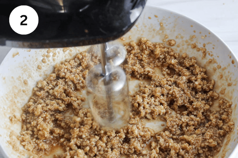 Electric beaters mixing butter, brown sugar and milk in a large bowl.