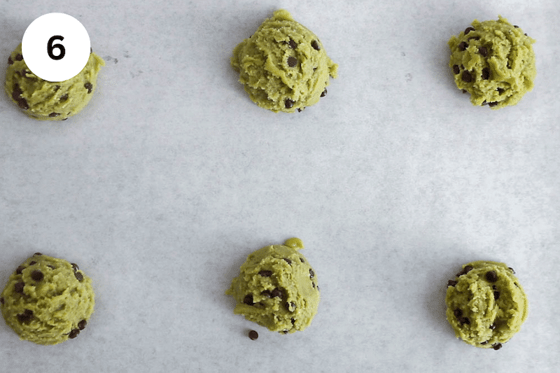 A baking sheet with 6 balls of green matcha cookie dough.