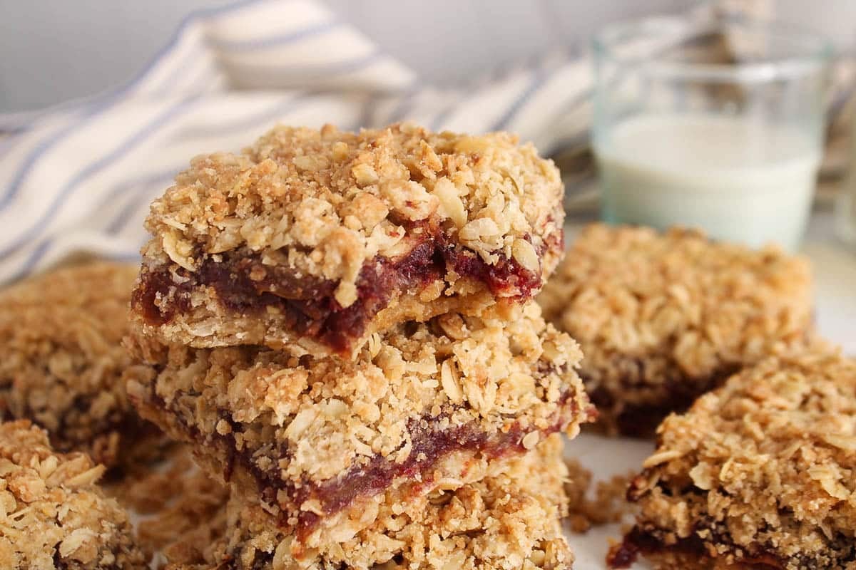 A pile of vegan date square with the top one having a bite taken off.