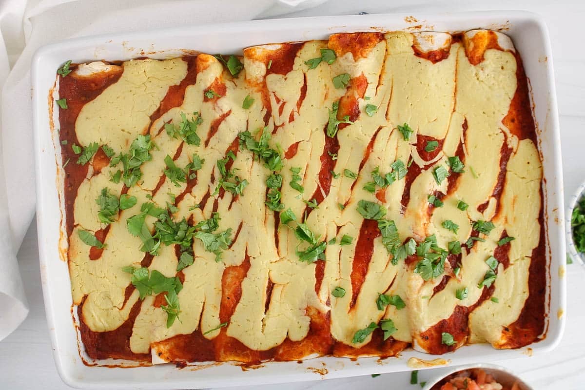 Large baked dish filled with vegan bean and rice enchiladas.