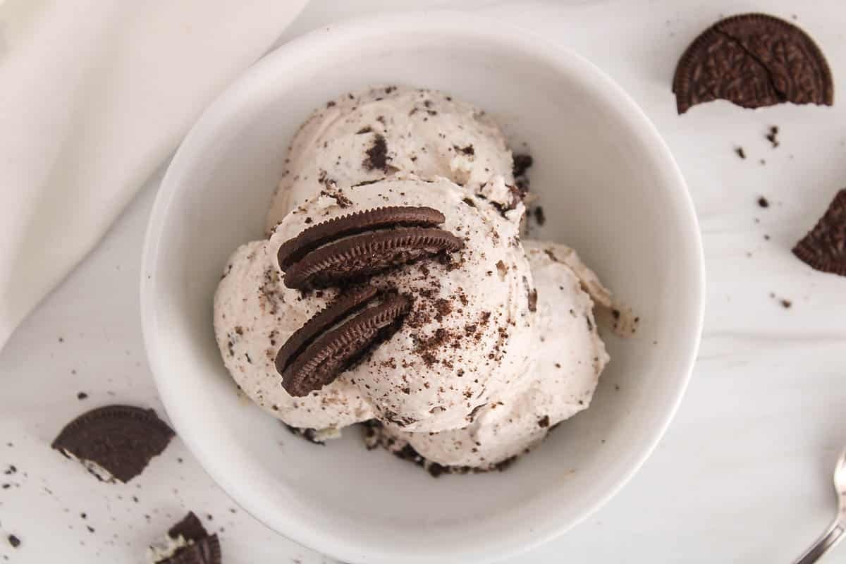 Bowl with a few scoops of vegan cookie and cream ice cream topped with Oreo cookies.