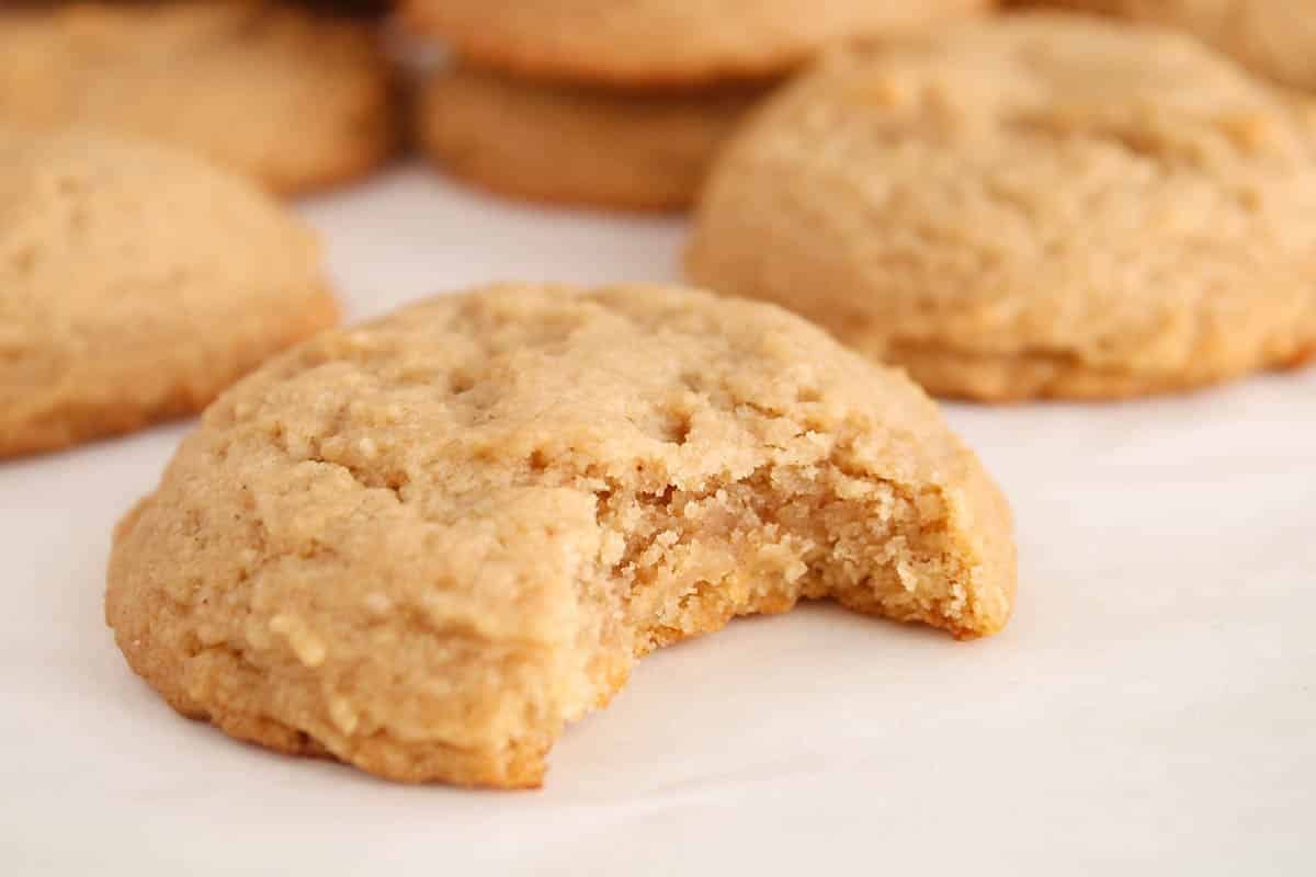 Vegan brown sugar cookie on a white table with a bite taken off.