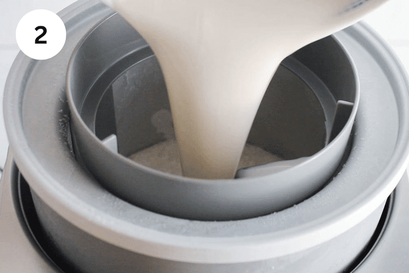 A creamy mixture pouring into an ice cream maker.