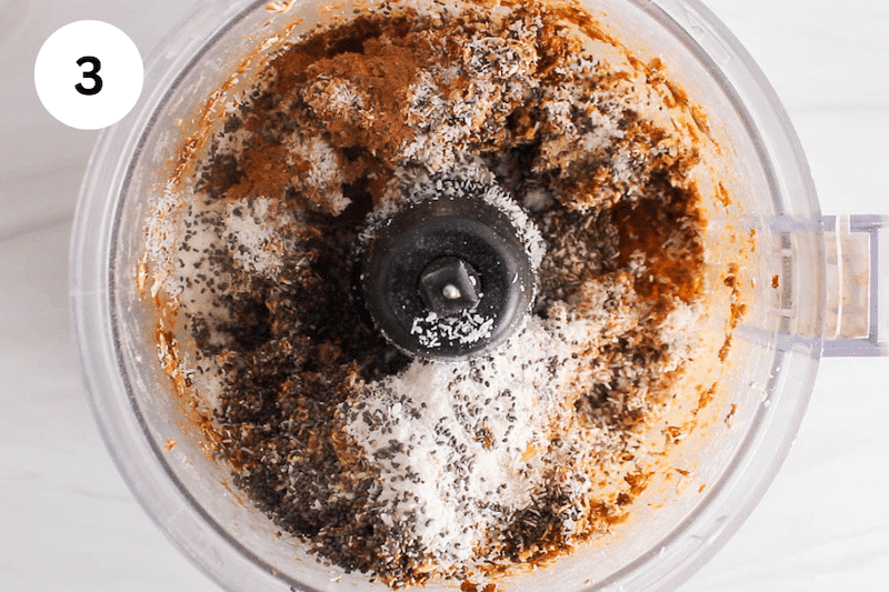 A food processor filled with dried apricot, chia seed, coconut and oats.