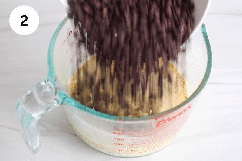 Chocolate chips pouring in a jar with a milk orange sauce.