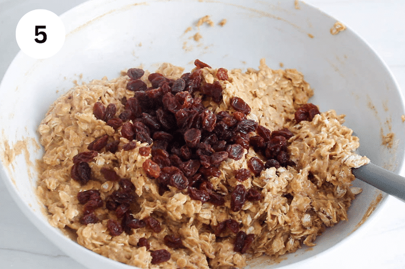 White bowl with cookie dough topped with raisins.