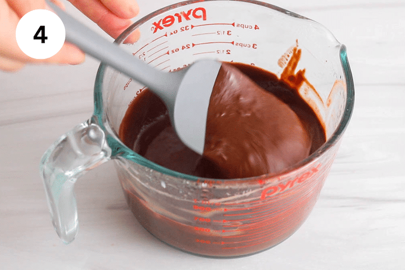 A spatula stirring in a jar of chocolate ganache.
