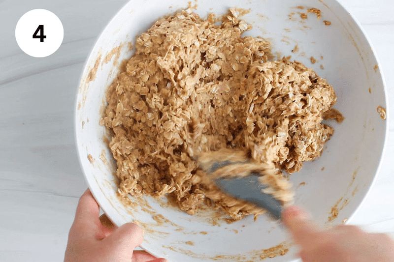 A spatula mixing cookie dough in a white bowl.