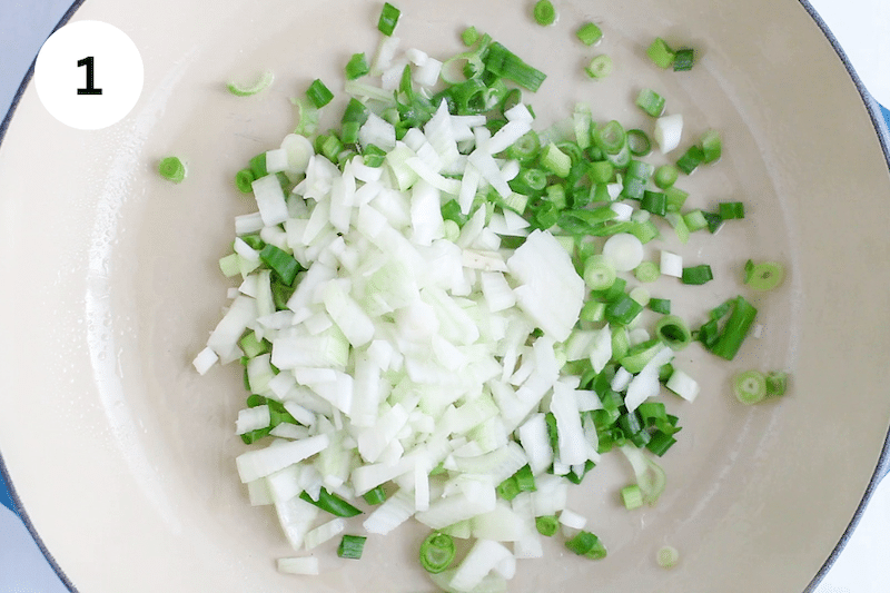 Large pan cooking onion and green onion.