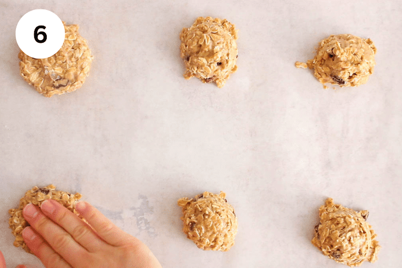 A hand shaping cookie dough into cookies.