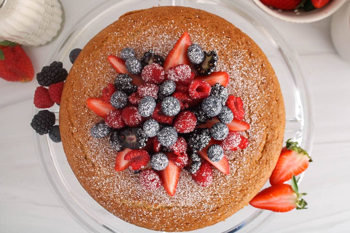 Round vegan olive oil cake garnished with berries.