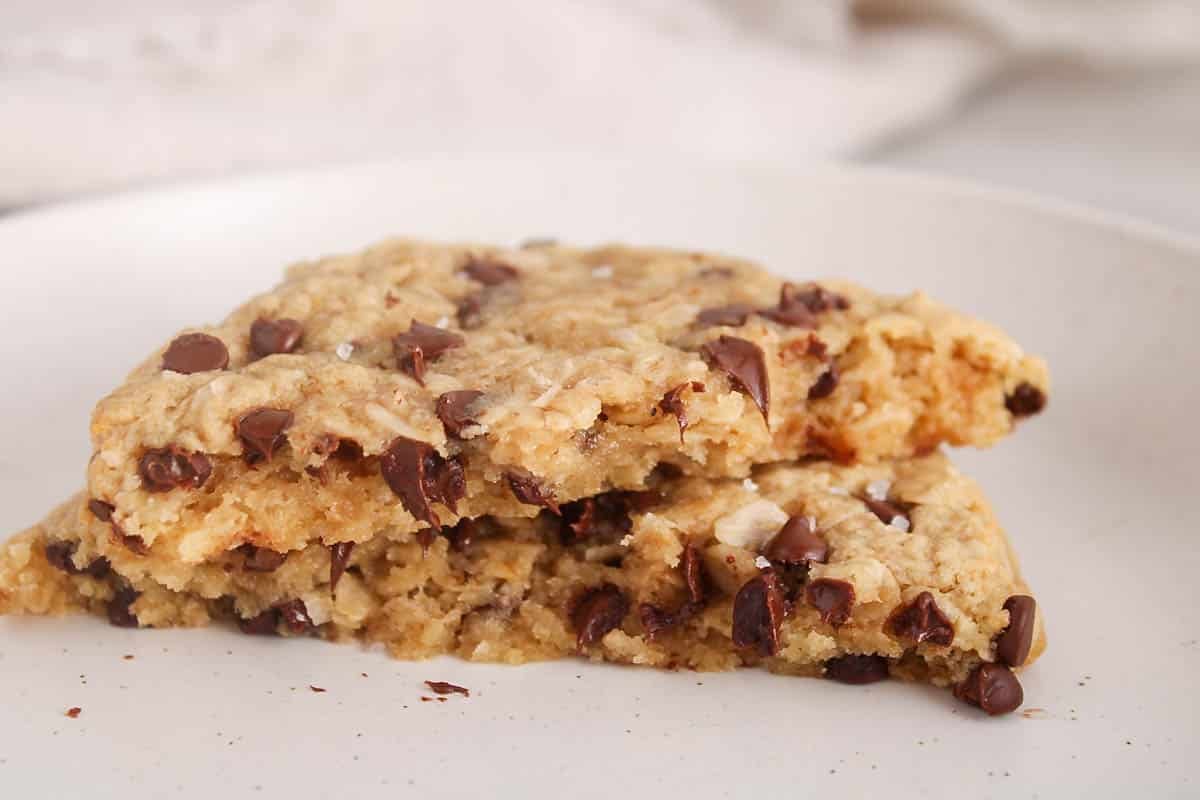 Single serve oatmeal cookie with chocolate chips broke up in 2 pieces and placed on a plate.