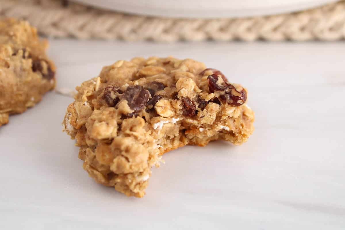 A vegan raisin and oat protein cookie with a bite taken off.
