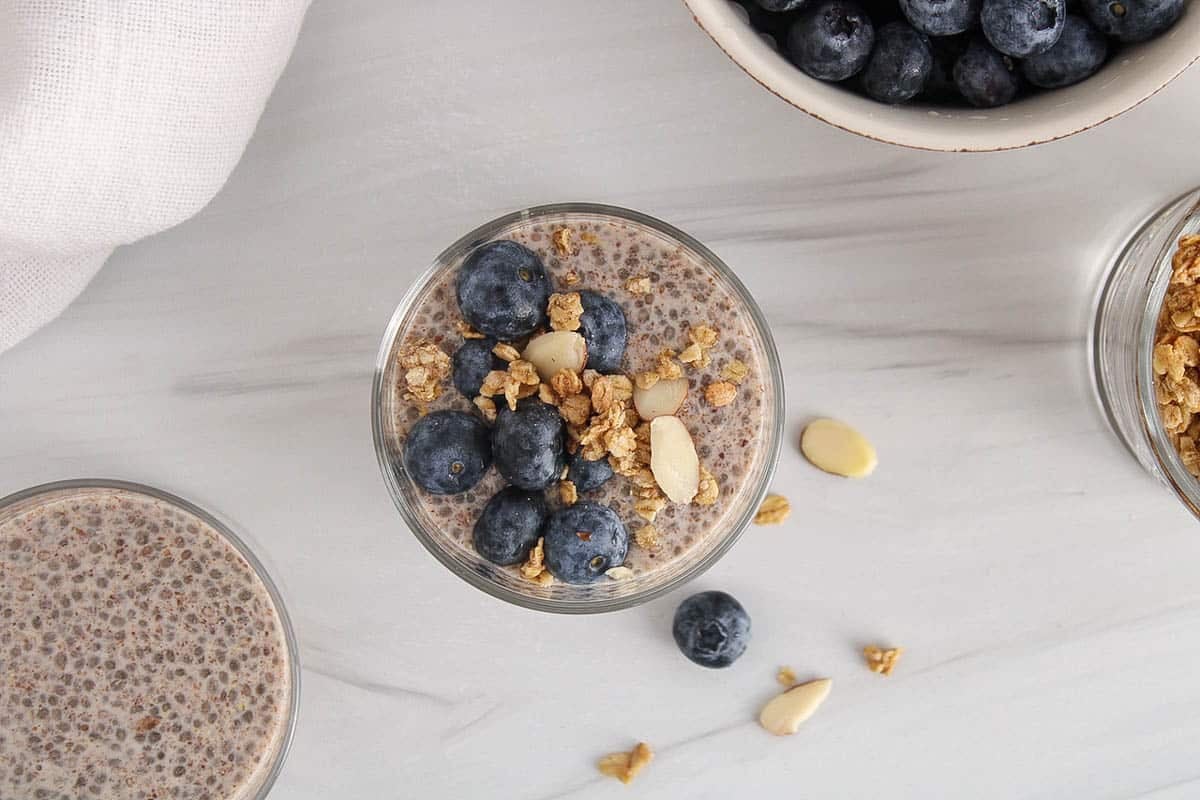 Jar filled with chia and flaxseed pudding garnished with blueberries and granola.