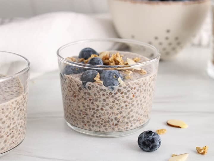 Jar filled with chia and flaxseed pudding garnished with blueberries and granola.