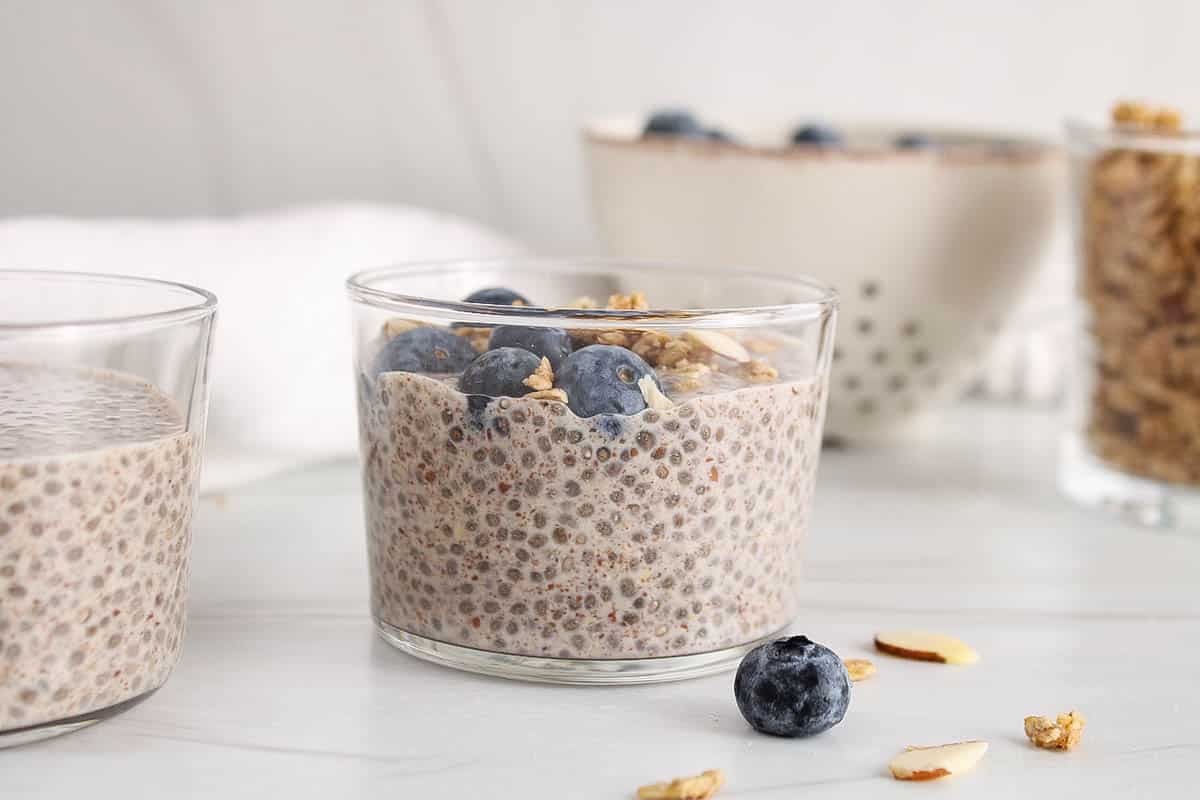 Jar filled with chia and flaxseed pudding garnished with blueberries and granola.