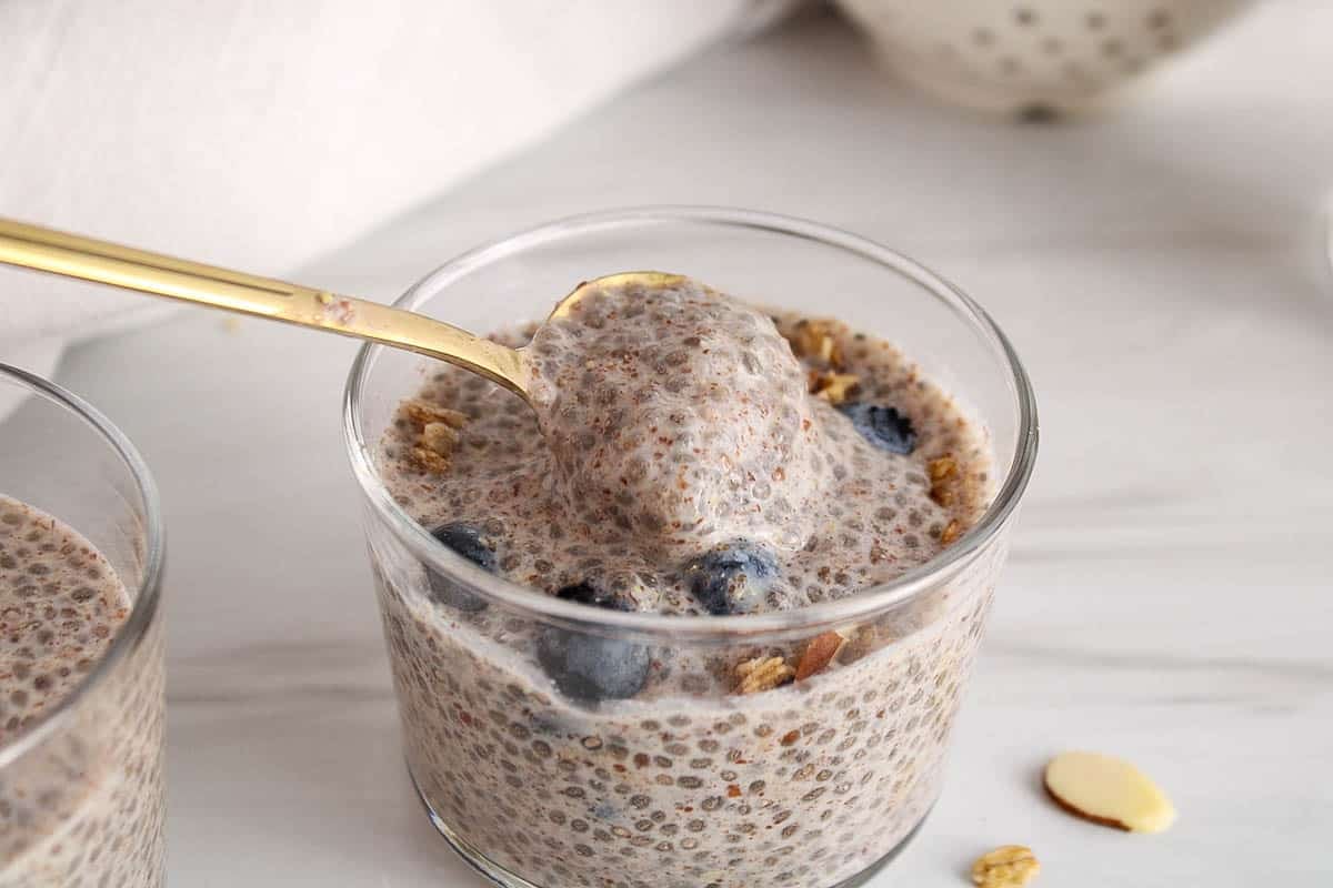 A spoon stirring in a jar of vegan chia and flaxseed pudding.