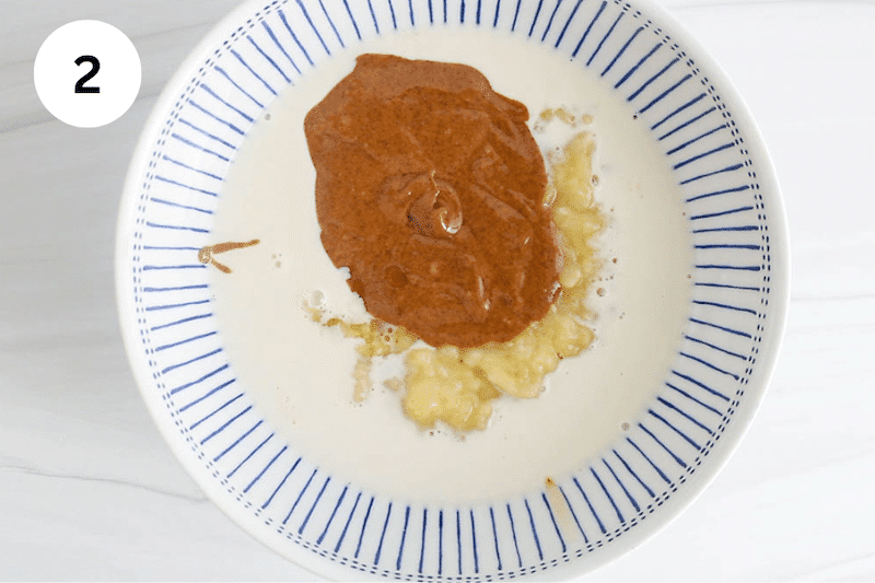 A bowl with mashed bananas, almond butter and milk.