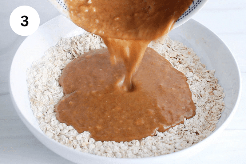 A wet mixture pouring over dry ingredients in a bowl.
