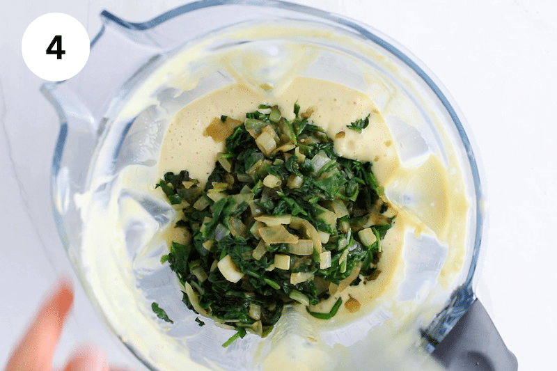 Blender with a tofu creamy mix and cooked spinach.