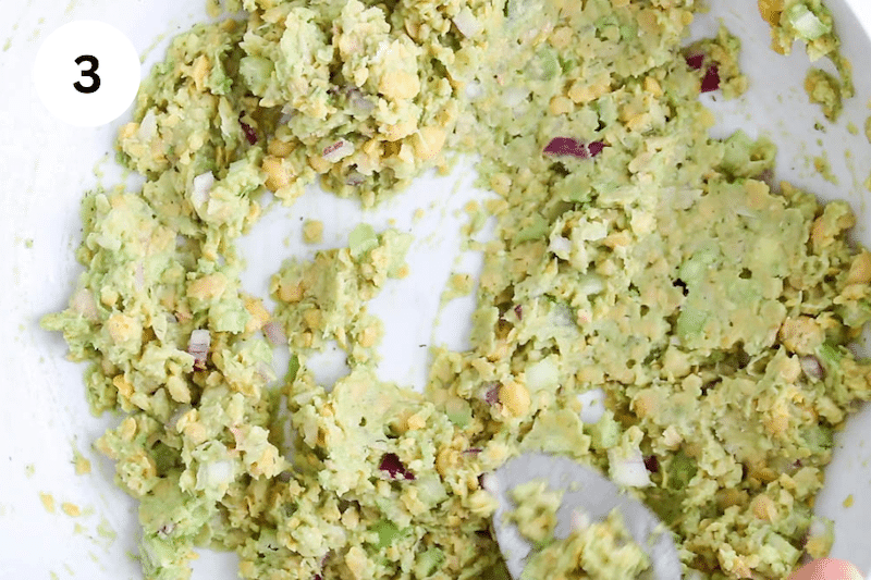 A large spoon mixing the sandwich filling ingredients.