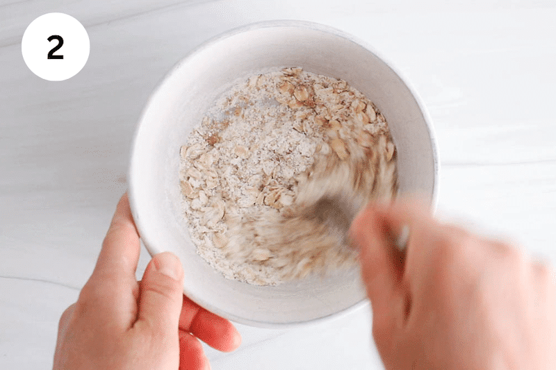A spoon mixing dry ingredients in a bowl.