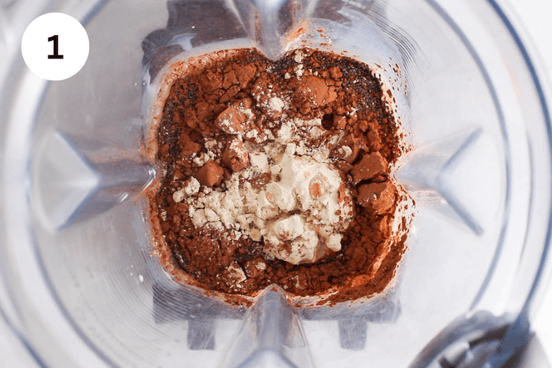 A blender container chia seeds, protein powder and cacao powder.