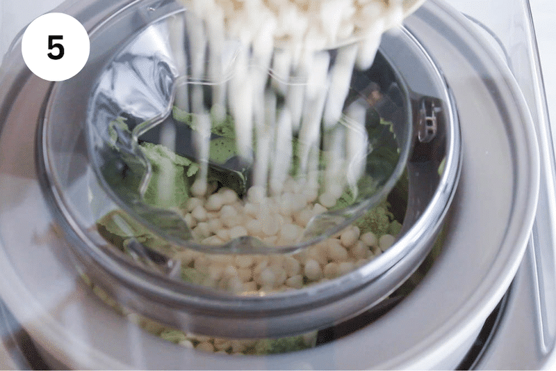 White chocolate chips falling into an ice cream maker.