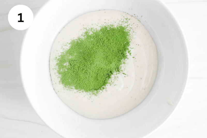 A white bowl with yogurt and matcha powder.