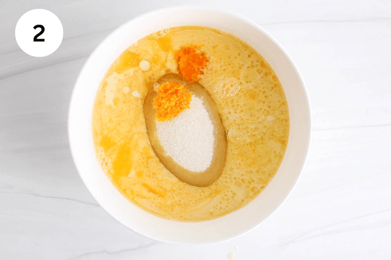 A white bowl with milk, orange jhuice and sugar.