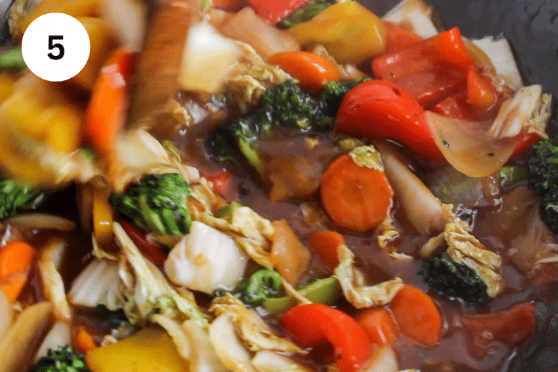 A large wok with saucy vegetables.