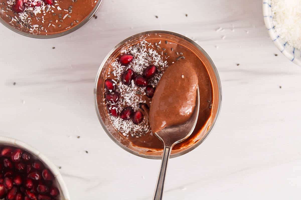 A spoon taking some blended chia chocolate pudding from a jar.