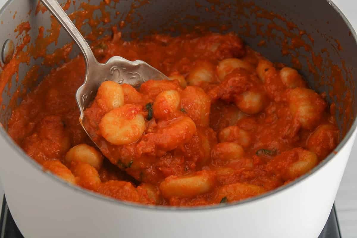 Red pesto gnocchi in a large pot.
