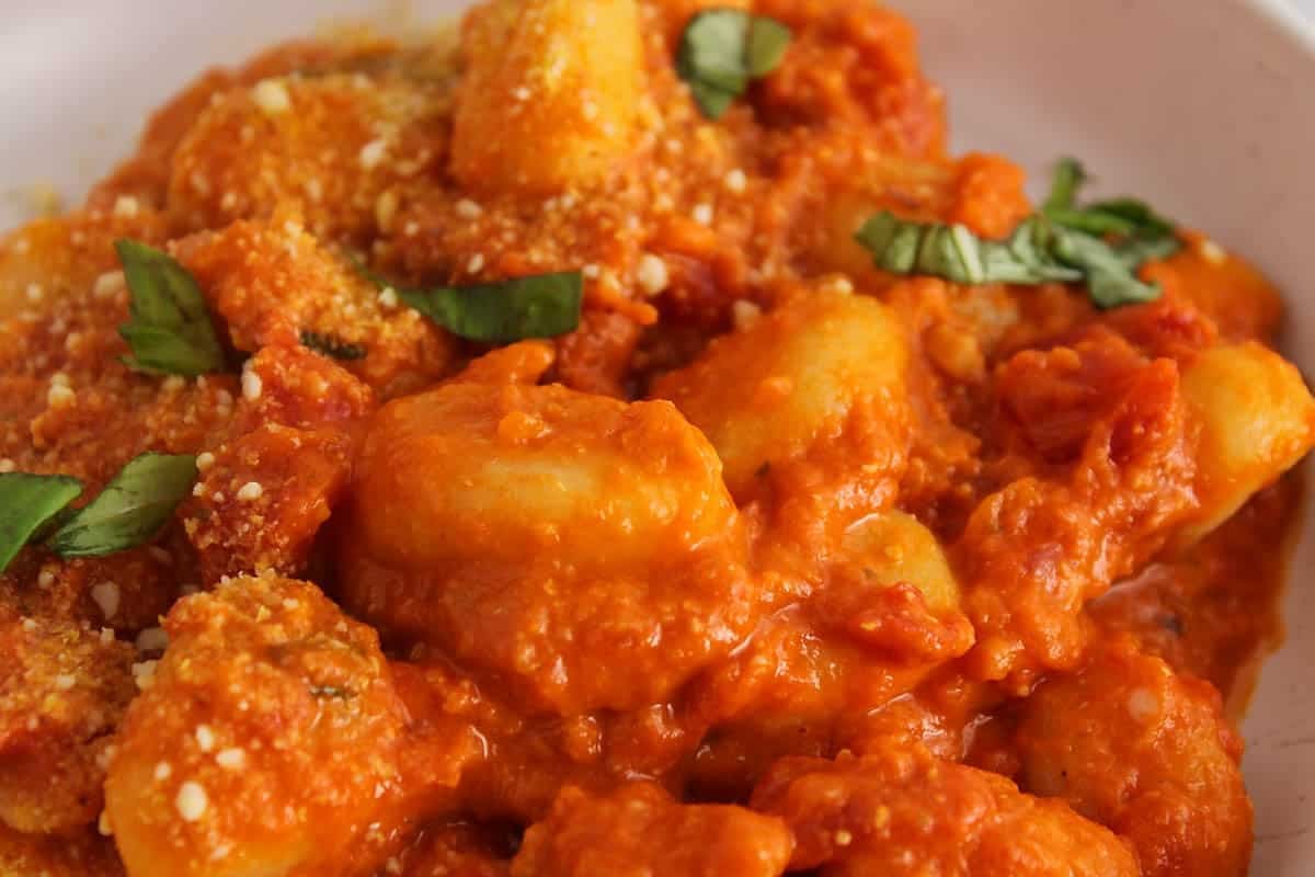 Vegan potato gnocchi in a red pesto and tomato sauce on a plate.