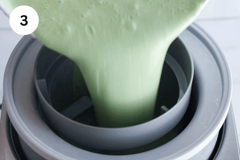 A green mixture pouring into an ice cream maker.