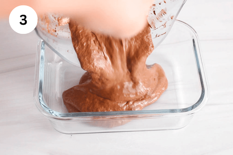 A blender pouring chocolate pudding in a storing container.