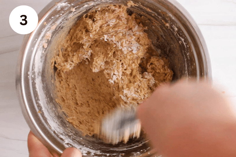 A spatula stirring in a bowl with a loaf batter.