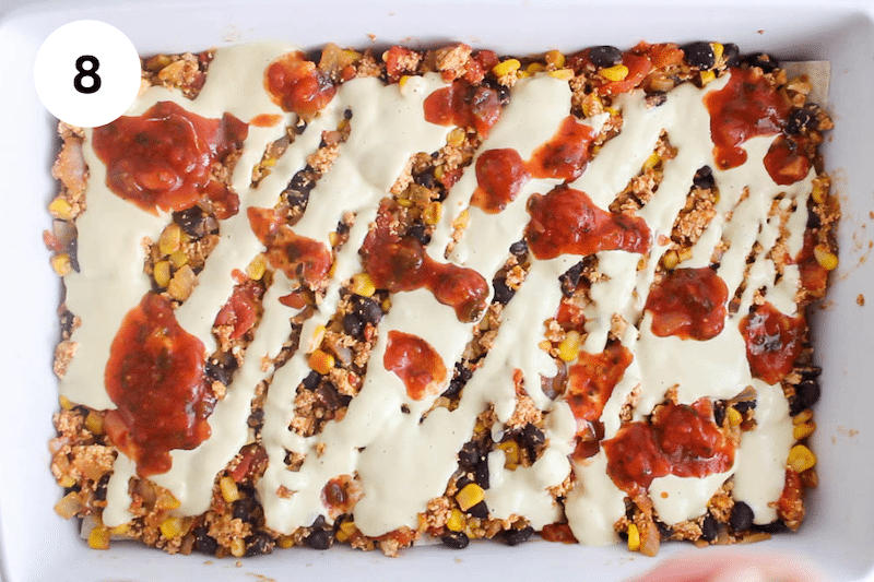 Baking dish with tofu mix covered with cheese sauce and salsa.