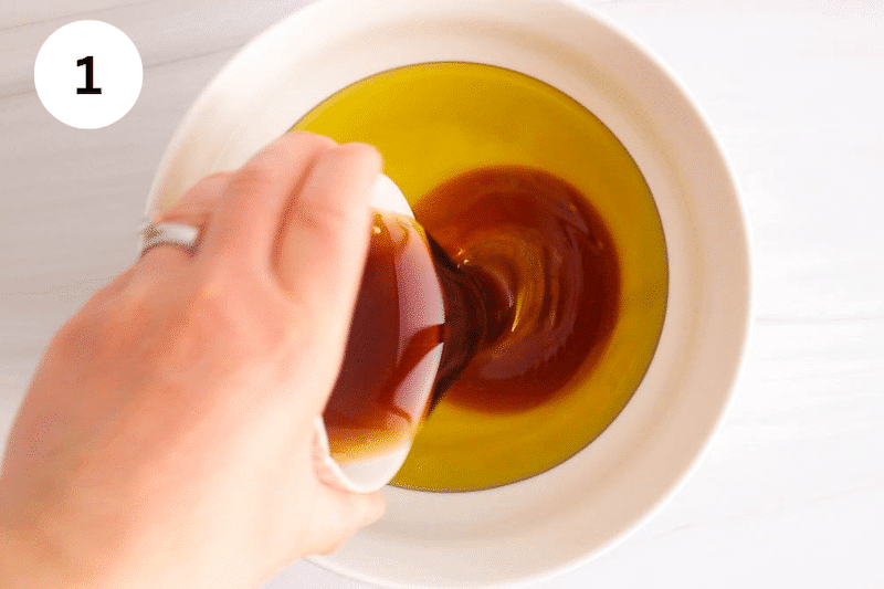 A bowl with olive oil and a smaller bowl pouring maple syrup into it.