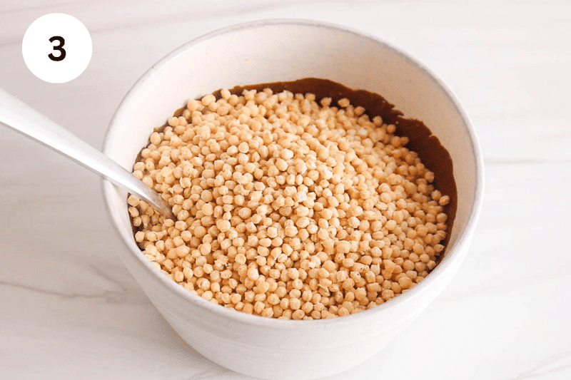 Quinoa puffs over a chocolate sauce in a bowl.