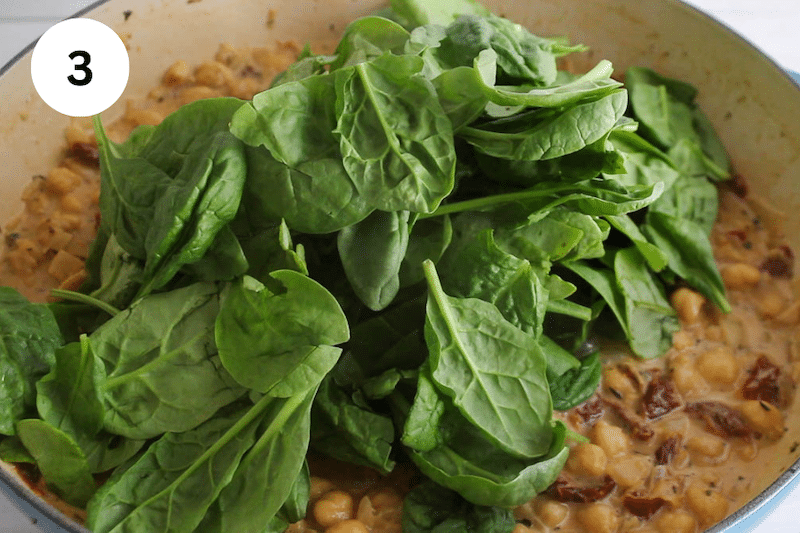 Spinach over a pan with saucy chickpeas.
