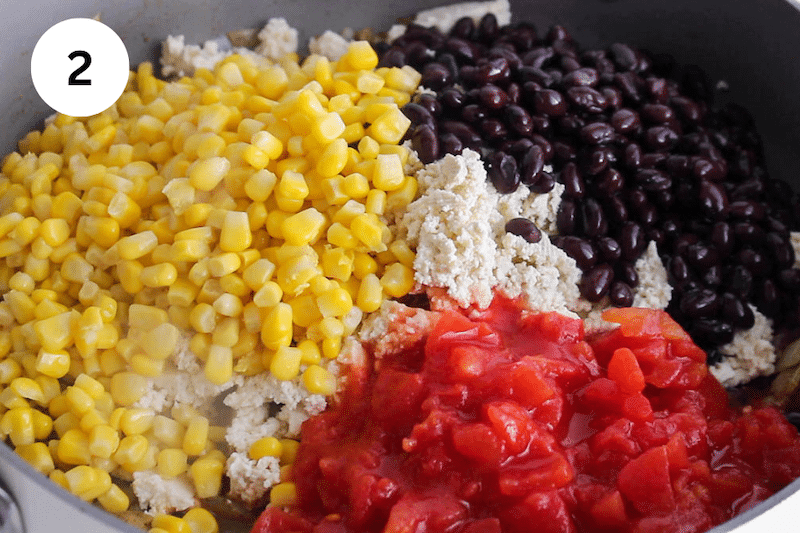 A large pan with tofu, beans, corn and tomatoes.