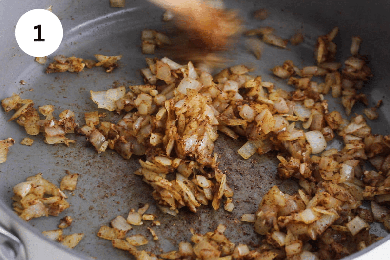 A large pan cooking onion with spices.