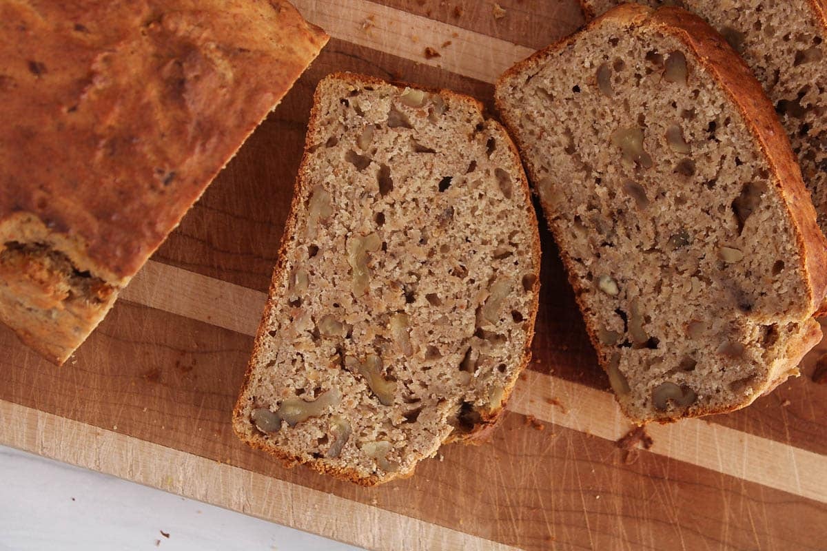A sliced vegan 4-ingredient banana nut bread on a cutting board.