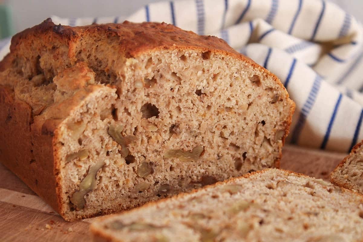 Halved banana nut bread on a cutting board.