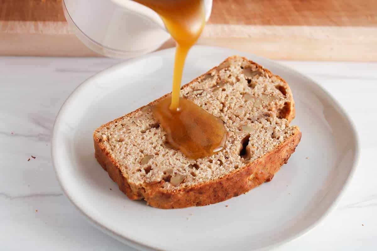 Olive oil caramel pouring over a slice of banana bread.