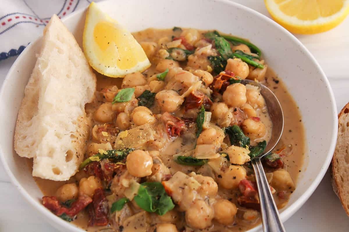 A spoon in a bowl of creamy vegan Tuscan chickpeas.