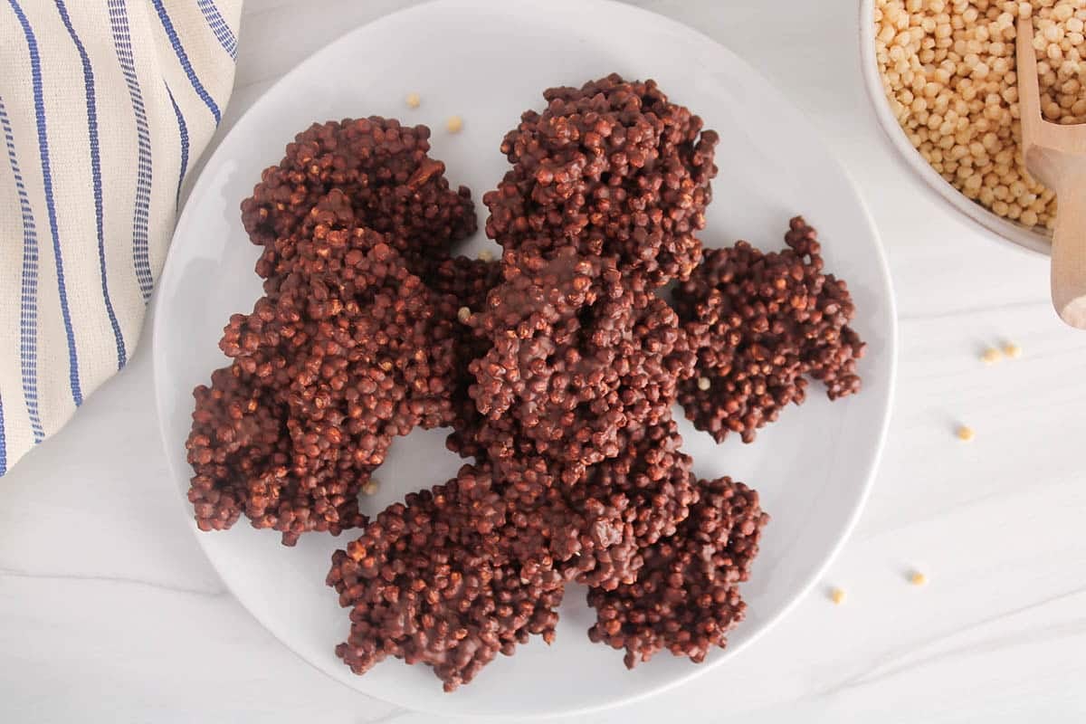 Quinoa chocolate bites on a plate with a bowl with more quinoa puffs.